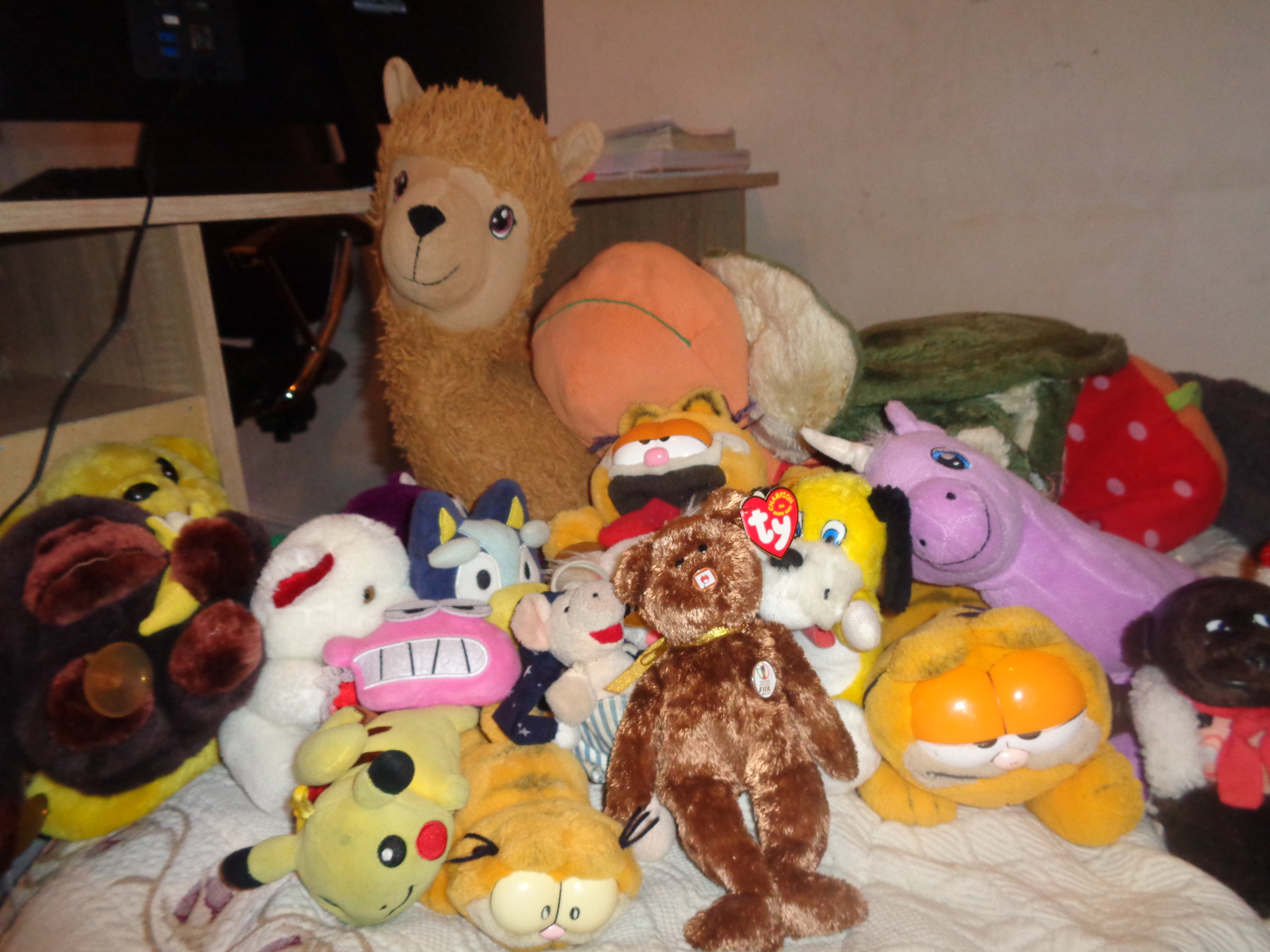 A pile of plushies on a bed.